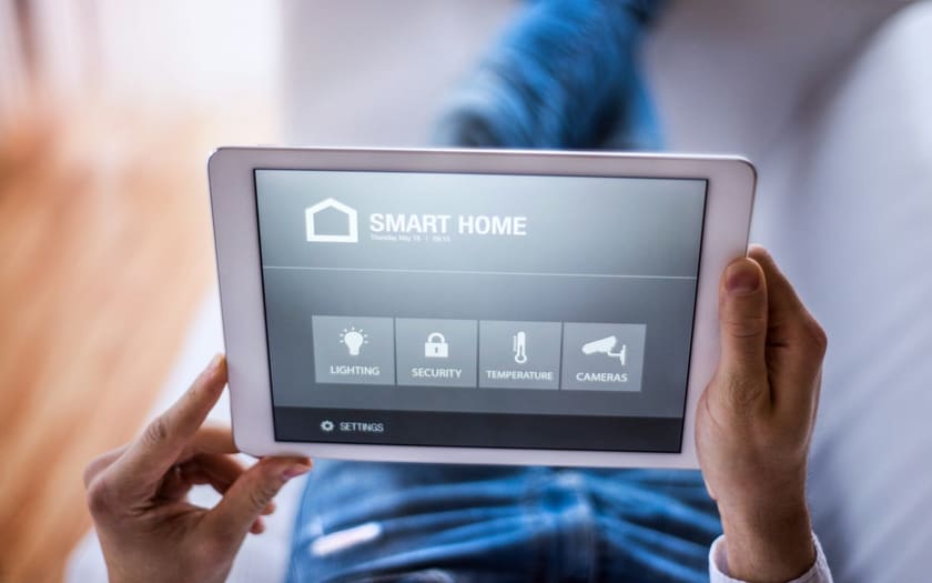 Person steuert Licht, Sicherheit und Kameras über ein Smart-Home-Tablet.