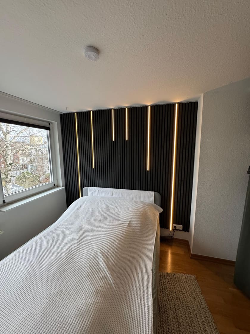 Montierte Akustikpaneele mit integrierten LED-Streifen und Wandsensor zur Steuerung.